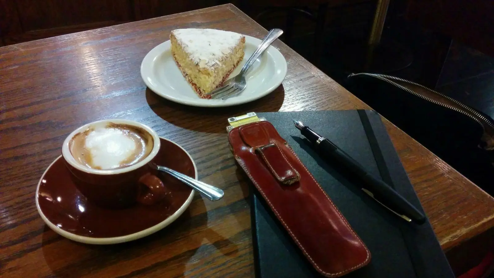 Notizbuch und Füllfederhalter neben einer Tasse Kaffee