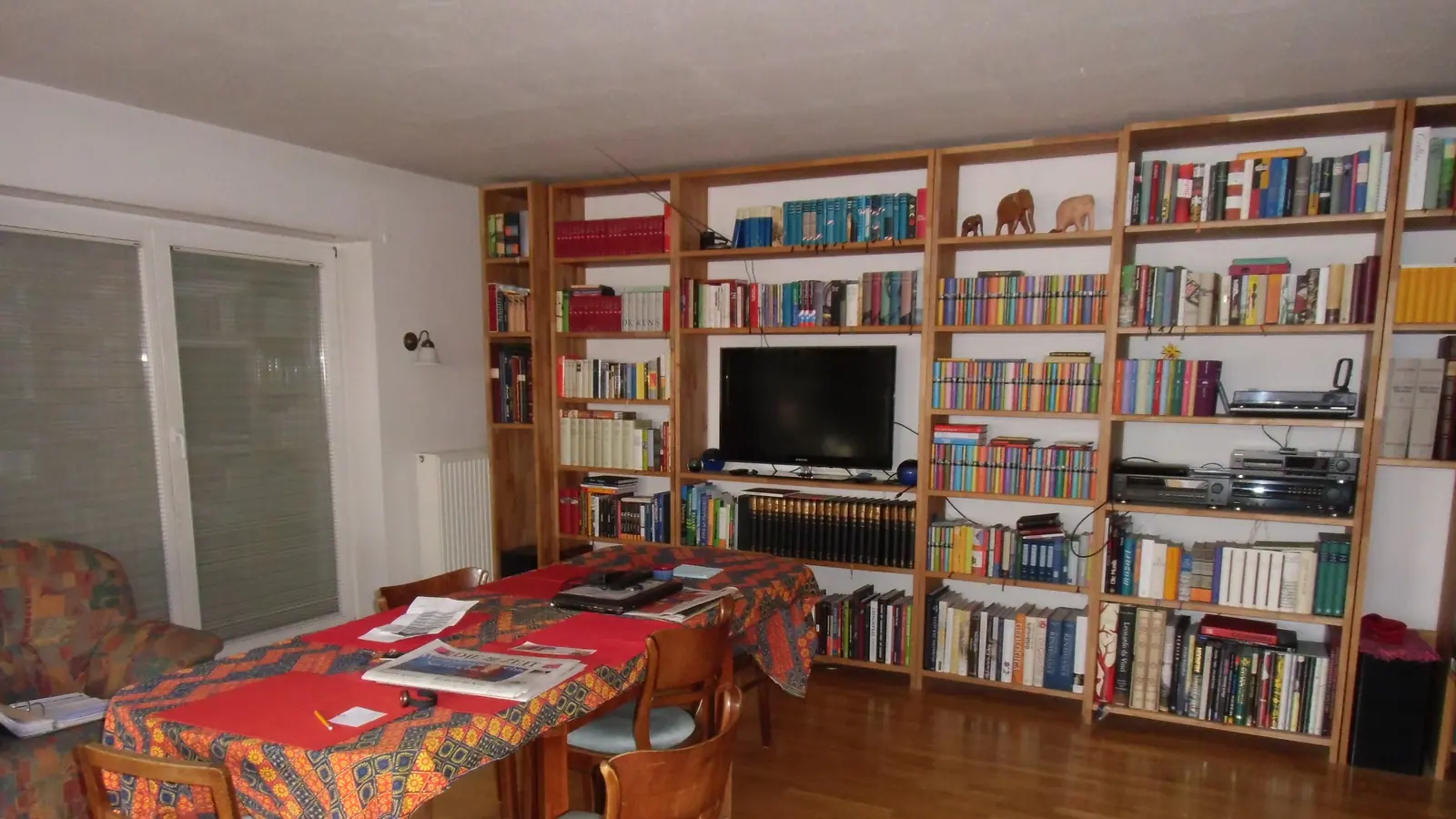 Wohnzimmer mit Bücherregalen und gedecktem Tisch